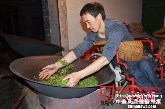 图为冉国防在正焙炒茶叶，进入焙干理条阶段。　李胜成　摄